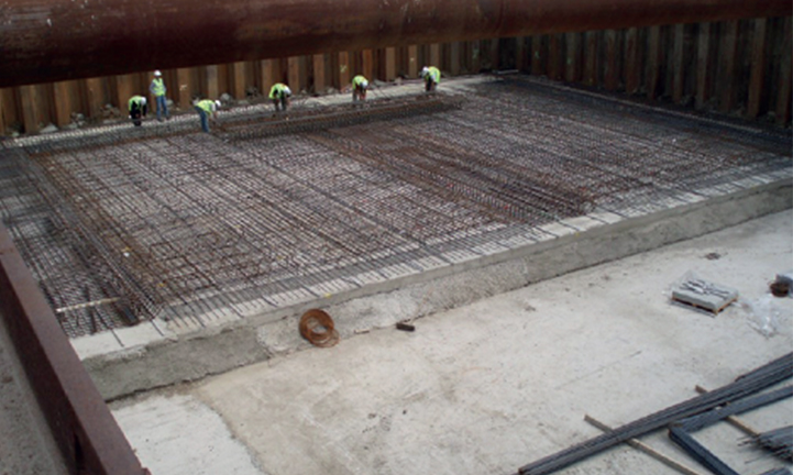 A construction worker pours concrete onto a prepared floor at a construction site.
