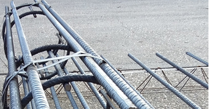 Several metal rods are stacked on a concrete floor